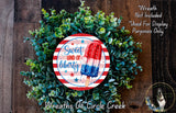 a wreath made of green foliage and a red, white, and blue popsicle stick decoration, with the text "Sweet Land of Liberty" and "Wreaths of Circle Creek" displayed on it.