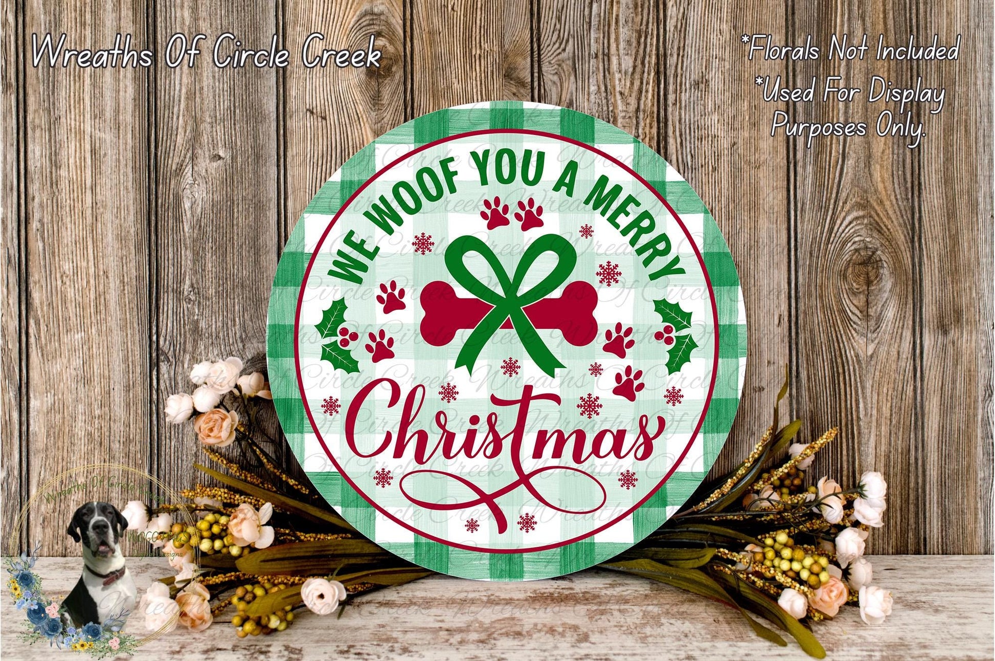 A circular Christmas-themed sign with the text "We Woof You a Merry Christmas" surrounded by a floral arrangement and a wooden background.