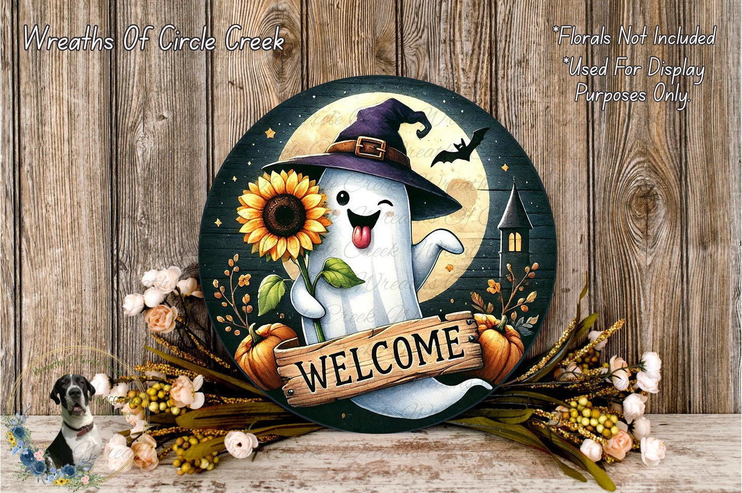 A round wooden sign featuring a ghost wearing a witch's hat and holding a sunflower, with the word "WELCOME" written on it. The sign is surrounded by a wreath of flowers and a pumpkin, and there is a bat flying above the ghost.
