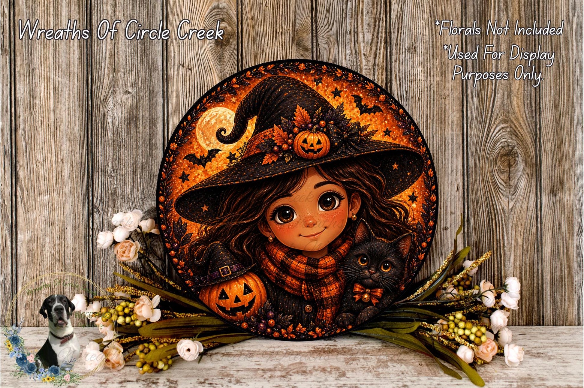 A round, decorative wreath featuring a young girl in a witch's hat, a jack-o-lantern, and a black cat, surrounded by flowers and a wooden background.