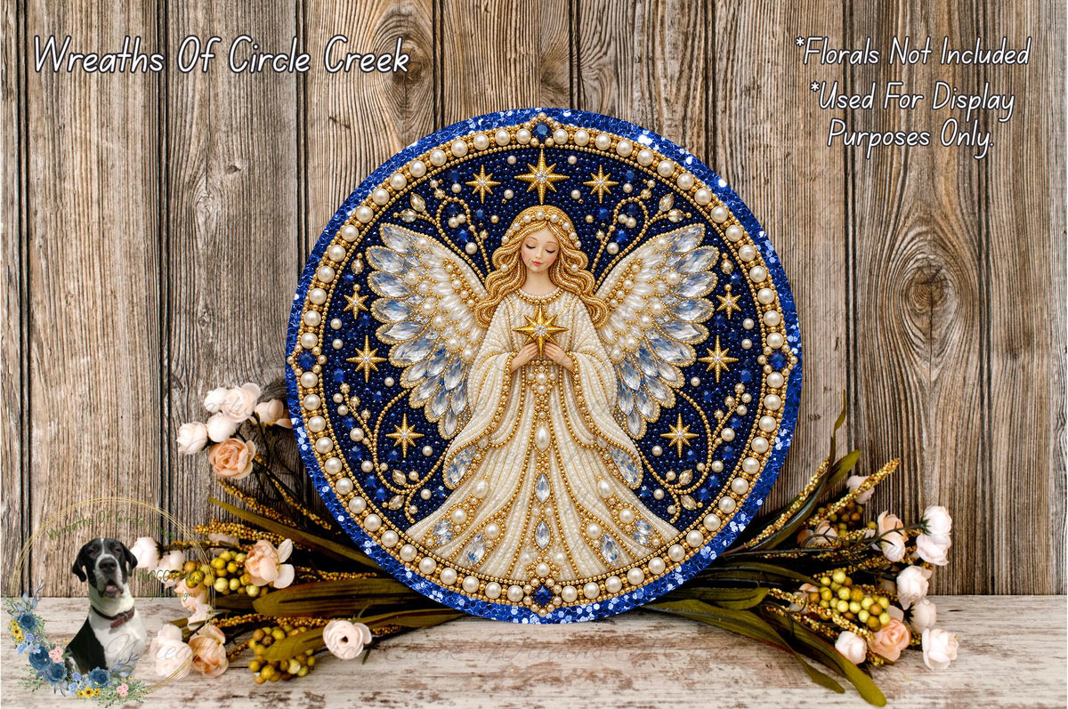 a decorative angel plaque with a blue and gold design, surrounded by flowers and placed on a wooden surface.