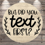 A circular wooden sign with the text "But Did You Text First?" written on it.