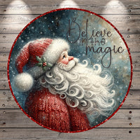 Santa Claus with a long white beard blowing a kiss, surrounded by snowflakes and the text "Believe in the magic"