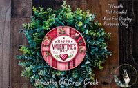 A wreath made of green leaves and flowers, with a red and white sign that says "Happy Valentine's Day". The wreath is displayed on a wooden surface, and there is a text overlay that reads "Wreath Not Included * Used For Display Purposes Only".