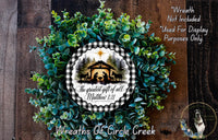 a wreath made of green foliage and a decorative plaque with a nativity scene and text.