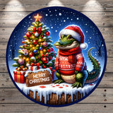 A whimsical Christmas scene featuring a crocodile wearing a Santa hat and scarf, sitting next to a decorated Christmas tree with ornaments and a star. The scene is set against a snowy background, and there is a "Merry Christmas" sign in the foreground.