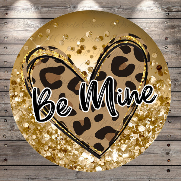 a heart-shaped design with a leopard print pattern and a glittery gold background. The phrase "Be Mine" is written in cursive font in the center of the heart.