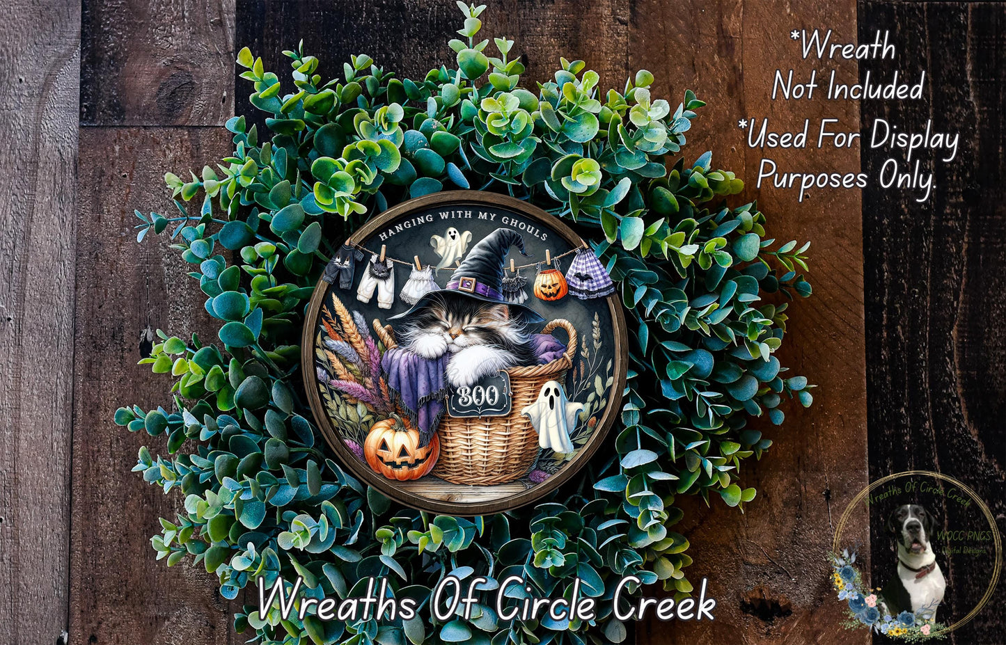 A Halloween-themed wreath with a cat wearing a witch's hat, surrounded by green foliage and pumpkins.