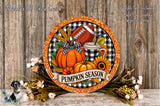 A decorative wreath with a football, pumpkin, sunflower, and other fall-themed items, along with a banner that says "Pumpkin Season". The wreath is set against a rustic wooden background, and there are some flowers and greenery surrounding it.