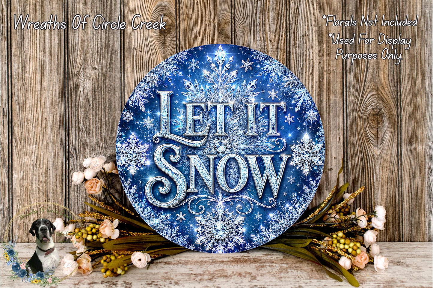 A decorative wreath with the text "Let it snow" in a blue and white color scheme, surrounded by flowers and placed on a wooden surface.