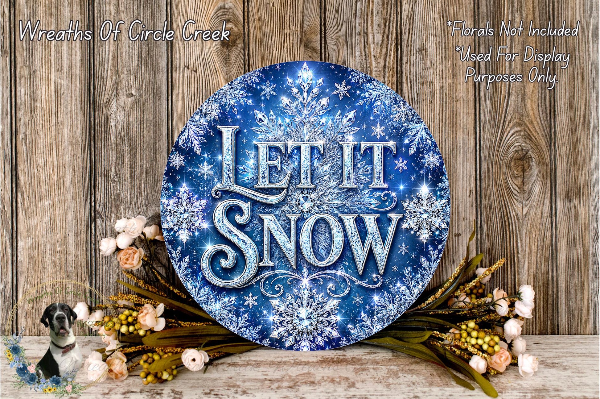 A decorative wreath with the text "Let it snow" in a blue and white color scheme, surrounded by flowers and placed on a wooden surface.