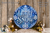 A decorative wreath with the text "Let it snow" in a blue and white color scheme, surrounded by flowers and placed on a wooden surface.