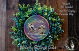 A festive wreath made of green foliage and featuring a Santa Claus sleigh pulled by reindeer, with a colorful circular design in the center displaying the text "Merry & Bright".