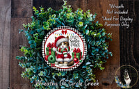 A wreath made of green leaves and a Santa Claus figurine, with the text "I Believe Santa Paws" and "Wreaths of Circle Creek" displayed on it.