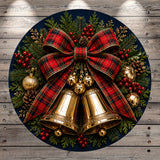 A festive Christmas wreath with a large red and black plaid bow, golden bells, pine cones, berries, and greenery.