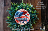 a wreath with a patriotic design, including an American flag and a horse, surrounded by greenery. The wreath is placed on a wooden surface, and there is a text overlay that reads "Welcome Wreath Not Included * Used For Display Purposes Only" and "Wreaths Of Circle Creek".