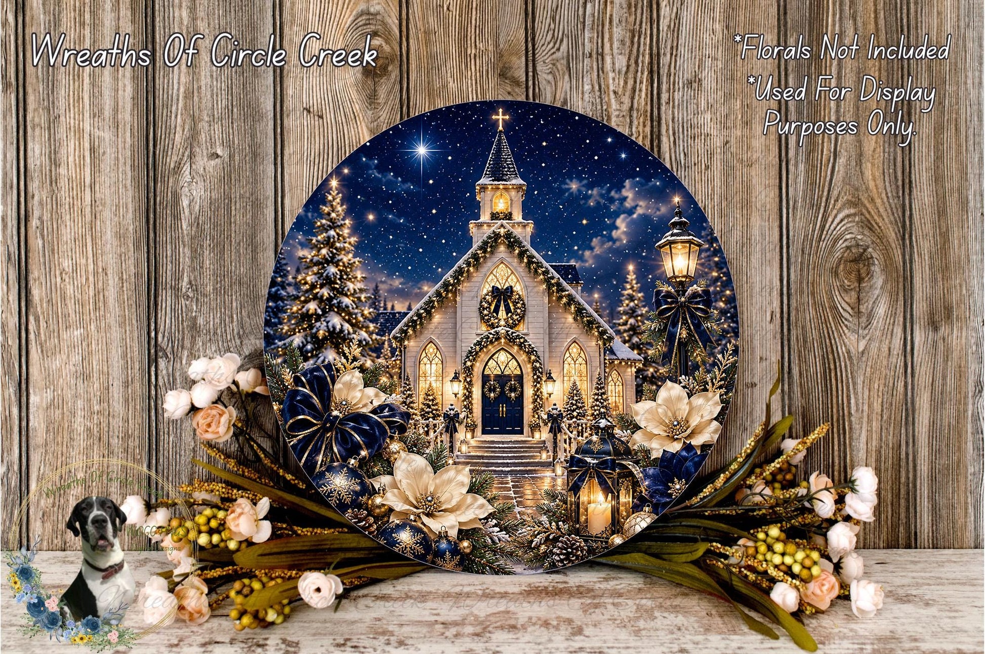 A decorative wreath featuring a church with a starry night sky, surrounded by flowers and greenery, placed on a wooden surface.