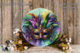 a vibrant and colorful round wall hanging with a large, ornate mask at the center, surrounded by a variety of flowers and foliage.