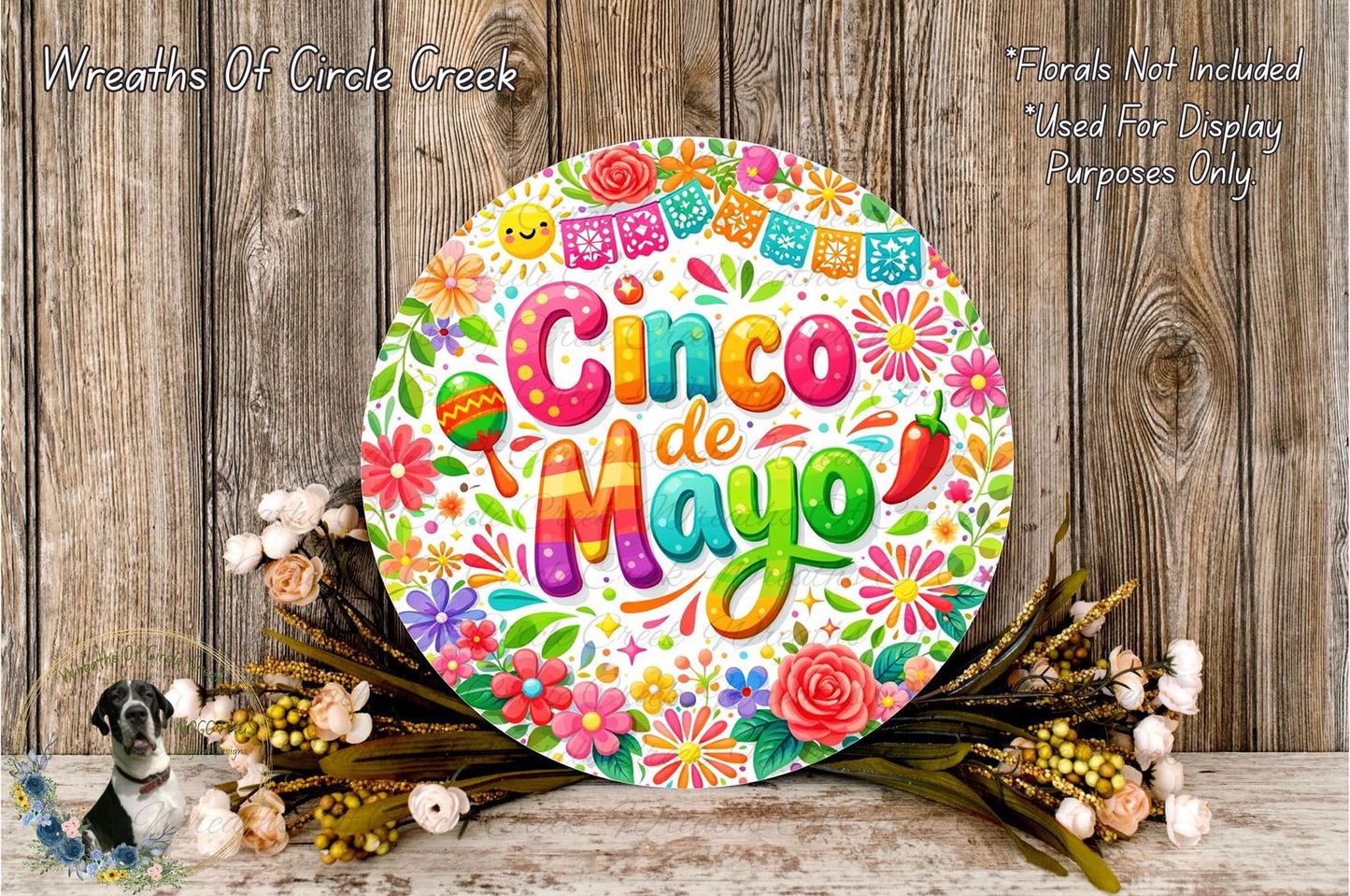 a vibrant and colorful round sign with the text "Cinco de Mayo" surrounded by a variety of flowers and decorations, placed on a wooden surface.