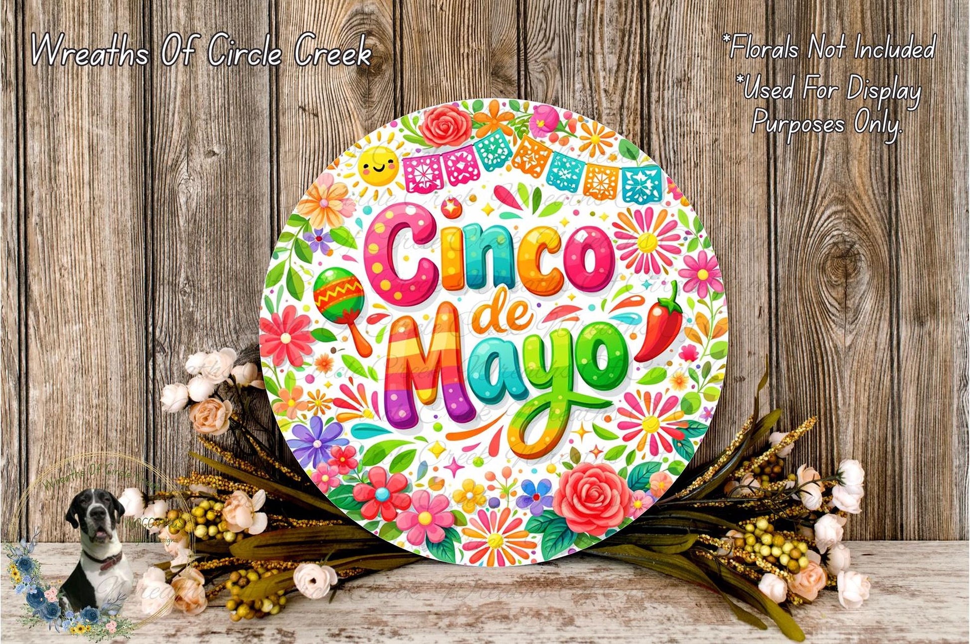 a vibrant and colorful round sign with the text "Cinco de Mayo" surrounded by a variety of flowers and decorations, placed on a wooden surface.
