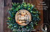 a wreath made of green leaves and pumpkins, with the word "Thankful" written on it. The wreath is displayed on a wooden surface, and there is a small dog in the bottom right corner of the image.