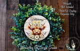 a wreath with a cow's head and flowers, surrounded by greenery, and a sign that reads "Welcome".