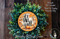 The image is a wreath made of various green plants and orange pumpkins, with a circular sign that says "It's Fall Yall" in the center.