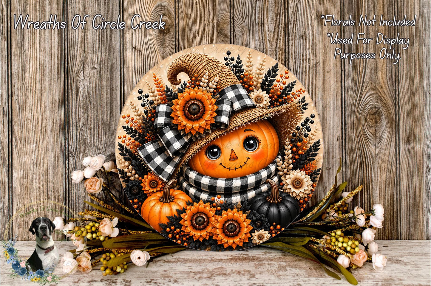 A decorative wreath featuring a pumpkin with a face, surrounded by autumn flowers and leaves, placed on a wooden surface.