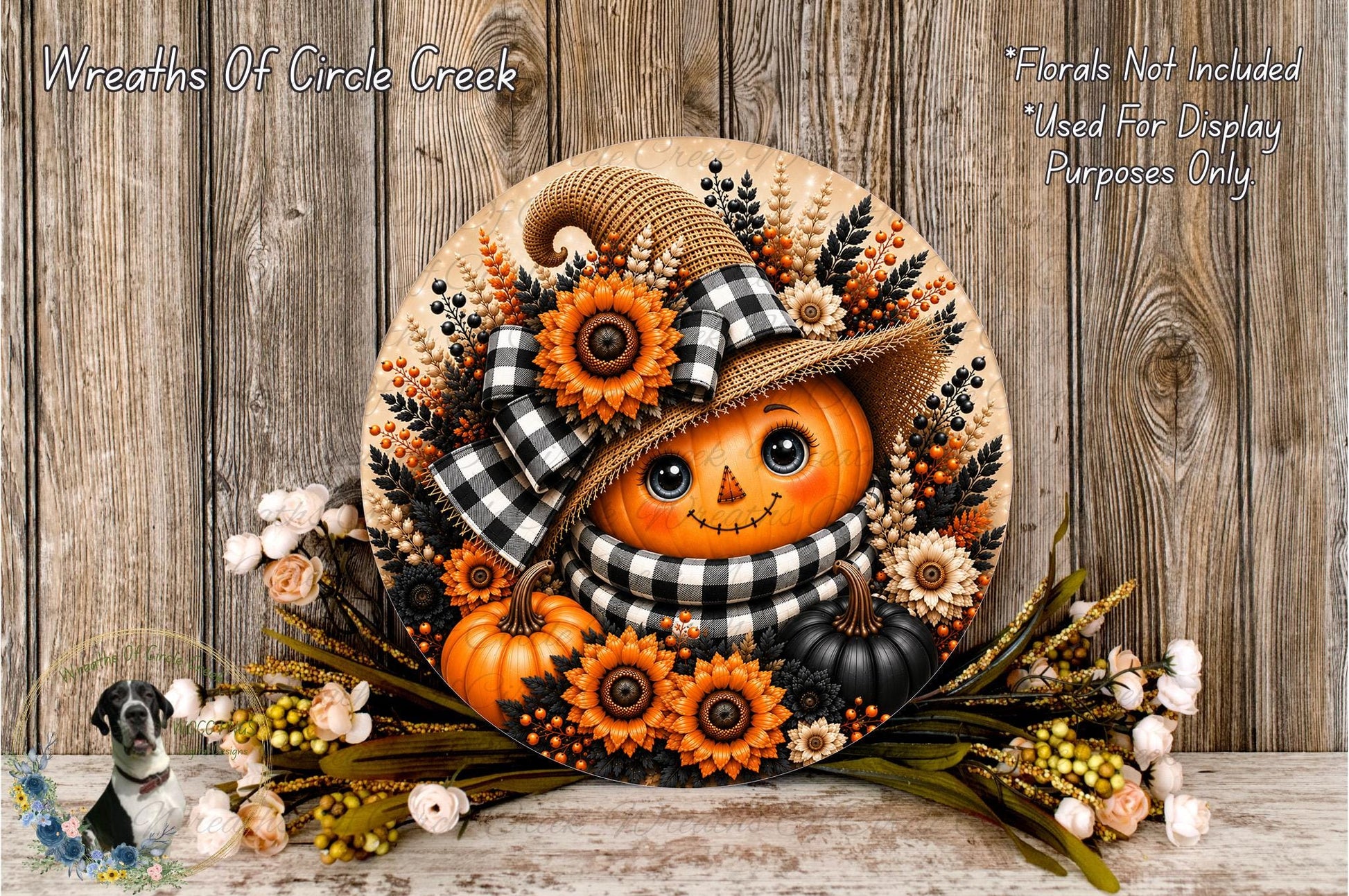 A decorative wreath featuring a pumpkin with a face, surrounded by autumn flowers and leaves, placed on a wooden surface.