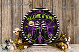 a decorative sign with the text "Welcome Witches" and a pair of witch's boots, surrounded by a floral arrangement and a wooden background.