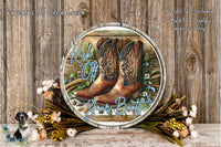 a round wooden sign with a pair of brown cowboy boots on it, surrounded by flowers and greenery. The sign has the text "Kick off your boots" written on it.