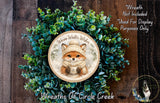 A wreath made of green plants and featuring a fox wearing a winter hat and scarf, with the text "Wreath Not Included * Used For Display Purposes Only" and "Wreaths of Circle Creek" written on it.
