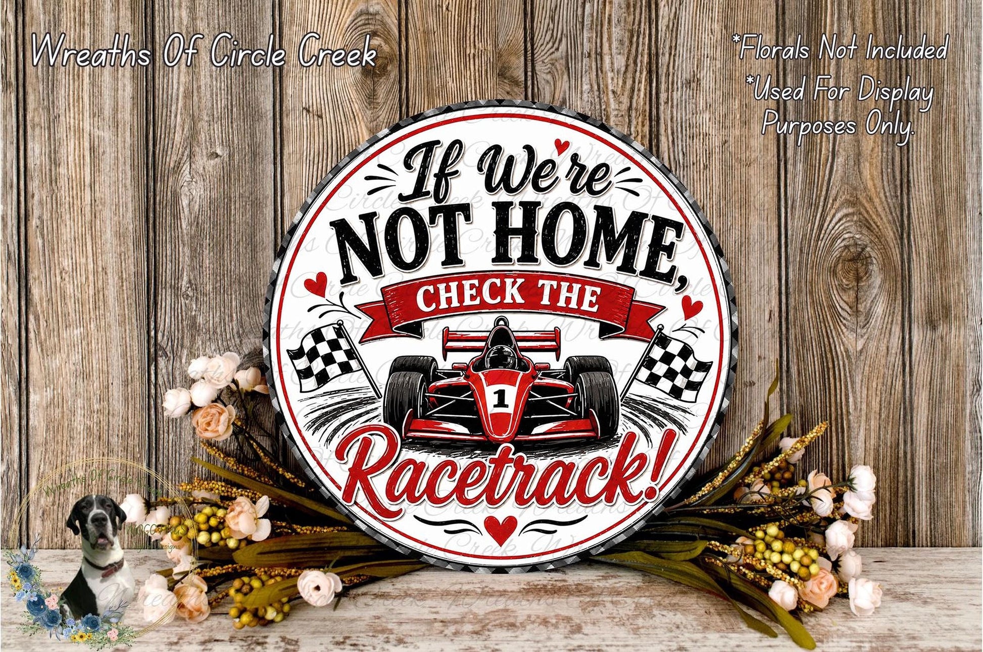 a decorative sign with a racing car design, surrounded by flowers and placed on a wooden surface.