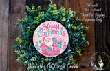 A Christmas wreath made of green foliage and featuring a Santa Claus illustration. The wreath is displayed on a wooden surface, and there is a text overlay that reads "Merry Christmas" and "Wreath Not Included * Used For Display Purposes Only".