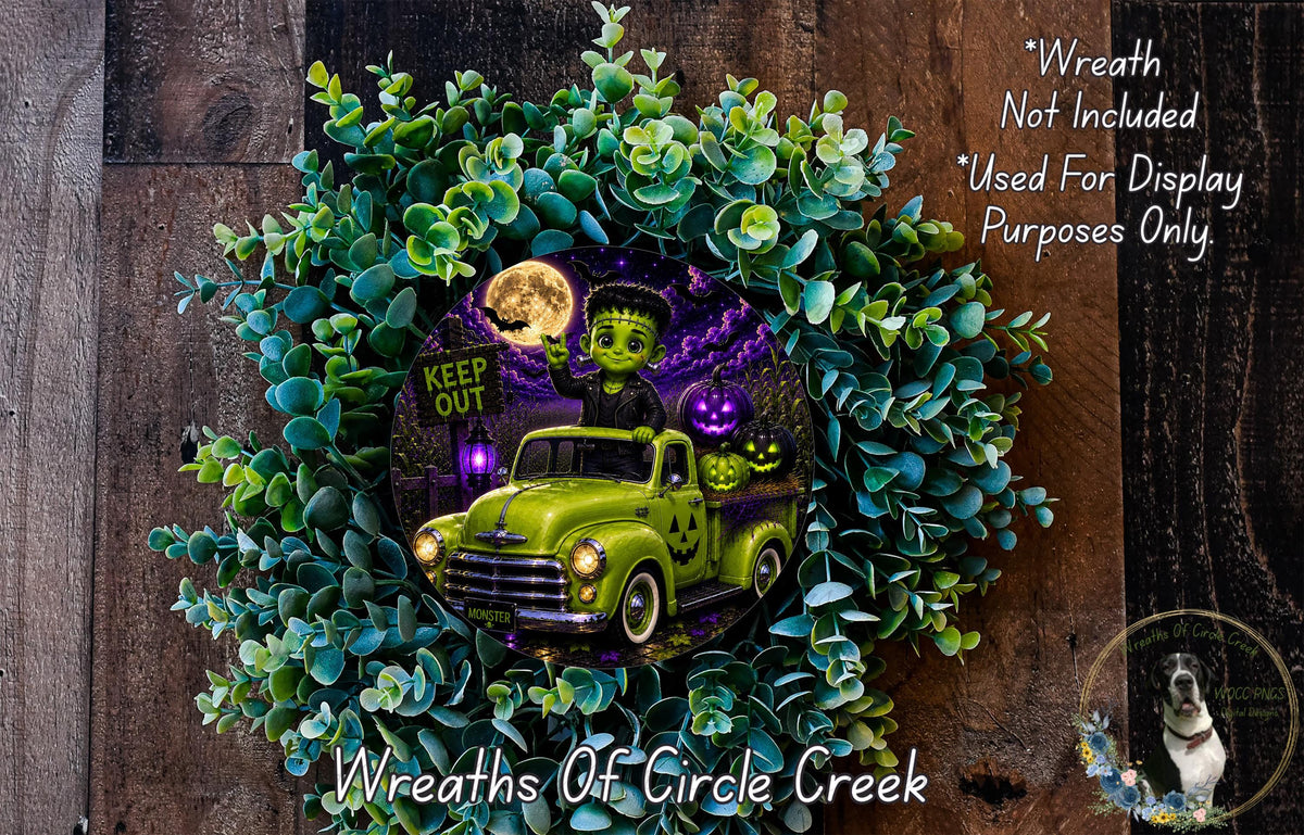 A Halloween-themed wreath made of green eucalyptus leaves, featuring a green truck with a skull and crossbones design, a skeleton, and a full moon.