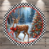 A deer with antlers stands in a snowy forest, adorned with a red bow, against a backdrop of a Christmas tree decorated with ornaments.