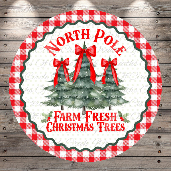A circular Christmas-themed label with a red and white checkered border, featuring three Christmas trees with red bows and the text "North Pole Farm Fresh Christmas Trees".