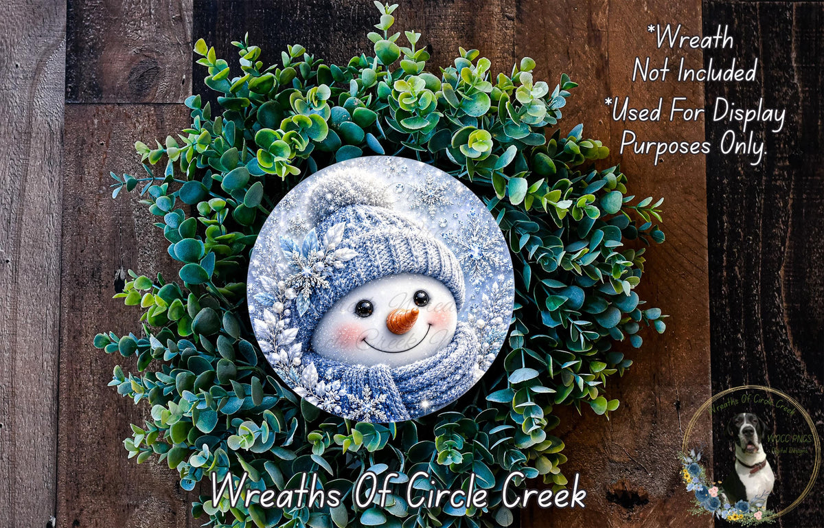 A wreath made of green plants and a snowman decoration, with a caption stating that the wreath is not included in the display and is used for display purposes only.