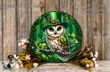 A decorative plate featuring an owl wearing a green hat with a leprechaun symbol, surrounded by shamrocks and other greenery, placed on a wooden surface with flowers.