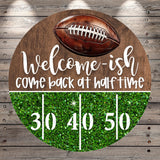 A welcome sign with a football and the text "Welcome-ish, come back at half-time" on a wooden background.