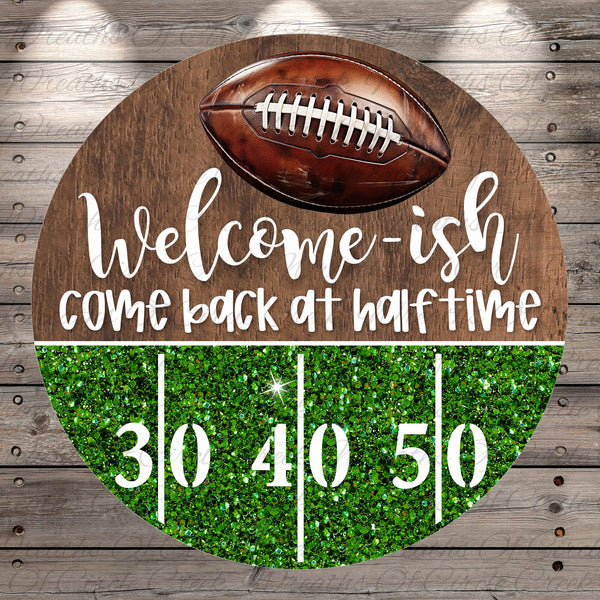 A welcome sign with a football and the text "Welcome-ish, come back at half-time" on a wooden background.