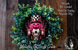 A wreath featuring a pumpkin with a black and white checkered hat, surrounded by green foliage.