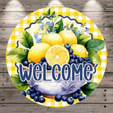 A round sign with a bowl of fruit, including lemons, blueberries, and green leaves, surrounded by a yellow and white checkered pattern. The sign has the text "WELCOME" written on it.