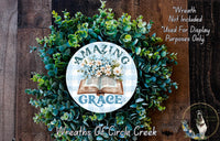 a wreath made of various green plants and flowers, with a circular sign in the center that says "Amazing Grace".