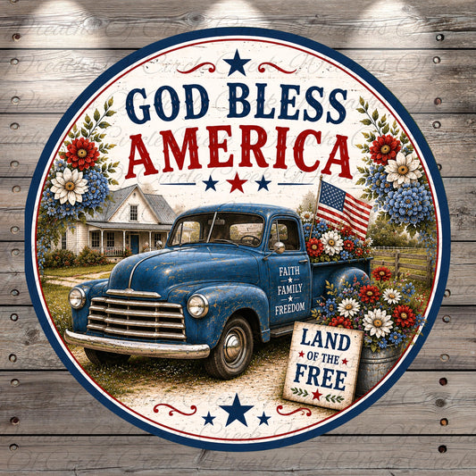 A circular patriotic sign with a blue vintage truck, flowers, and an American flag, along with the text "God Bless America" and "Land of the Free".