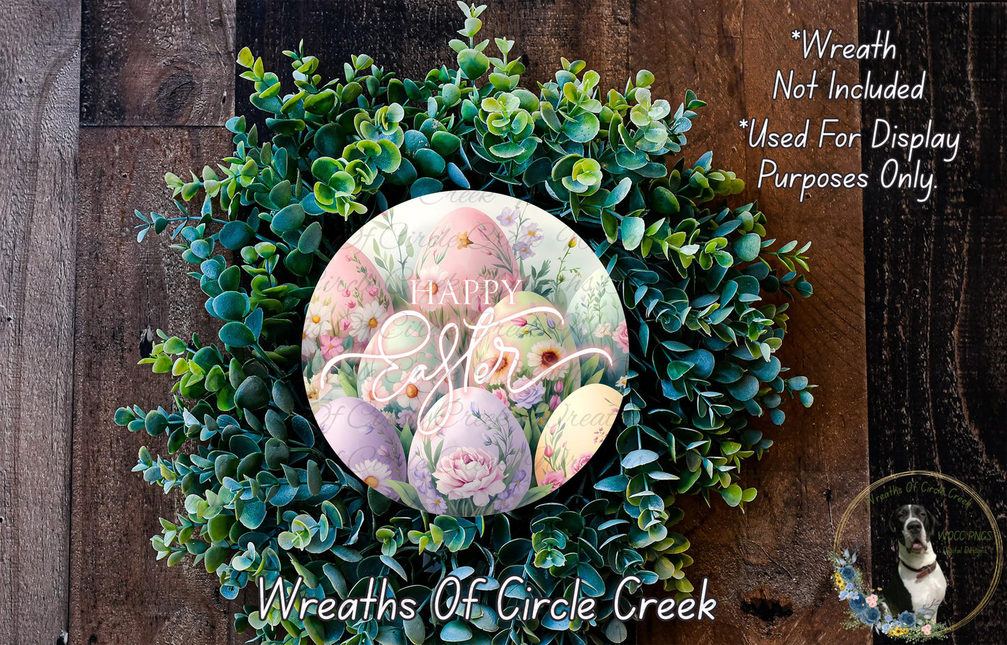 a wreath made of green leaves and flowers, with a circular design in the center that includes the text "Happy Easter" surrounded by Easter eggs. The wreath is displayed on a wooden surface, and there is a small dog in the bottom right corner of the image.