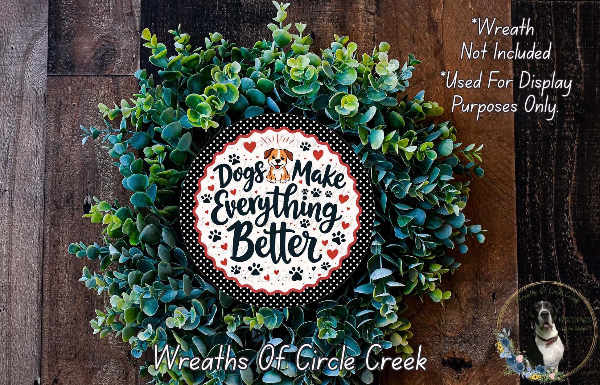 A wreath made of green leaves and a circular sign with the text "Dogs Make Everything Better" is displayed on a wooden surface.