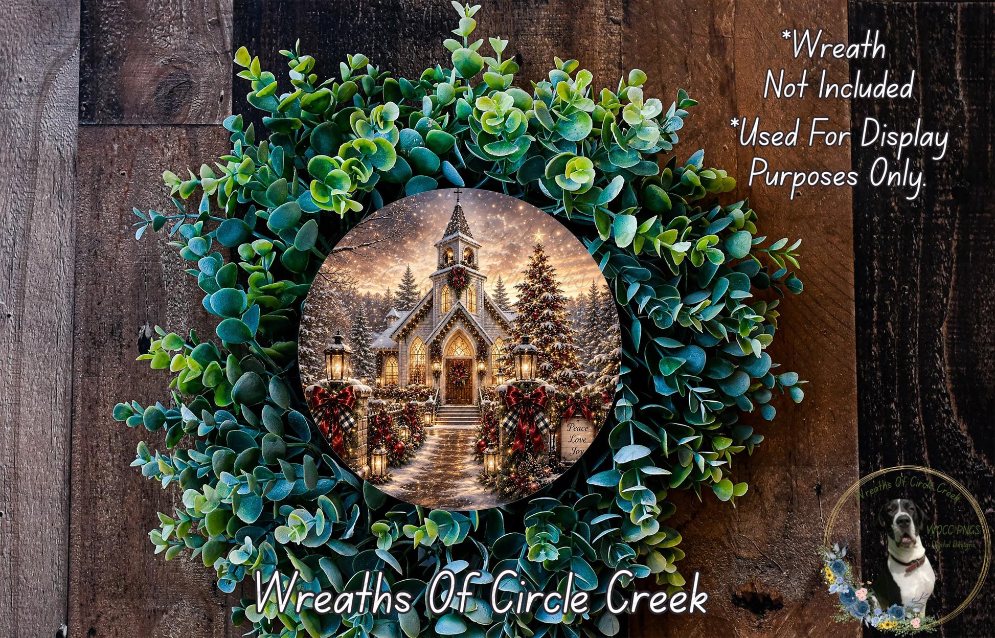 A wreath with a circular image of a church surrounded by greenery and flowers, placed on a wooden surface.
