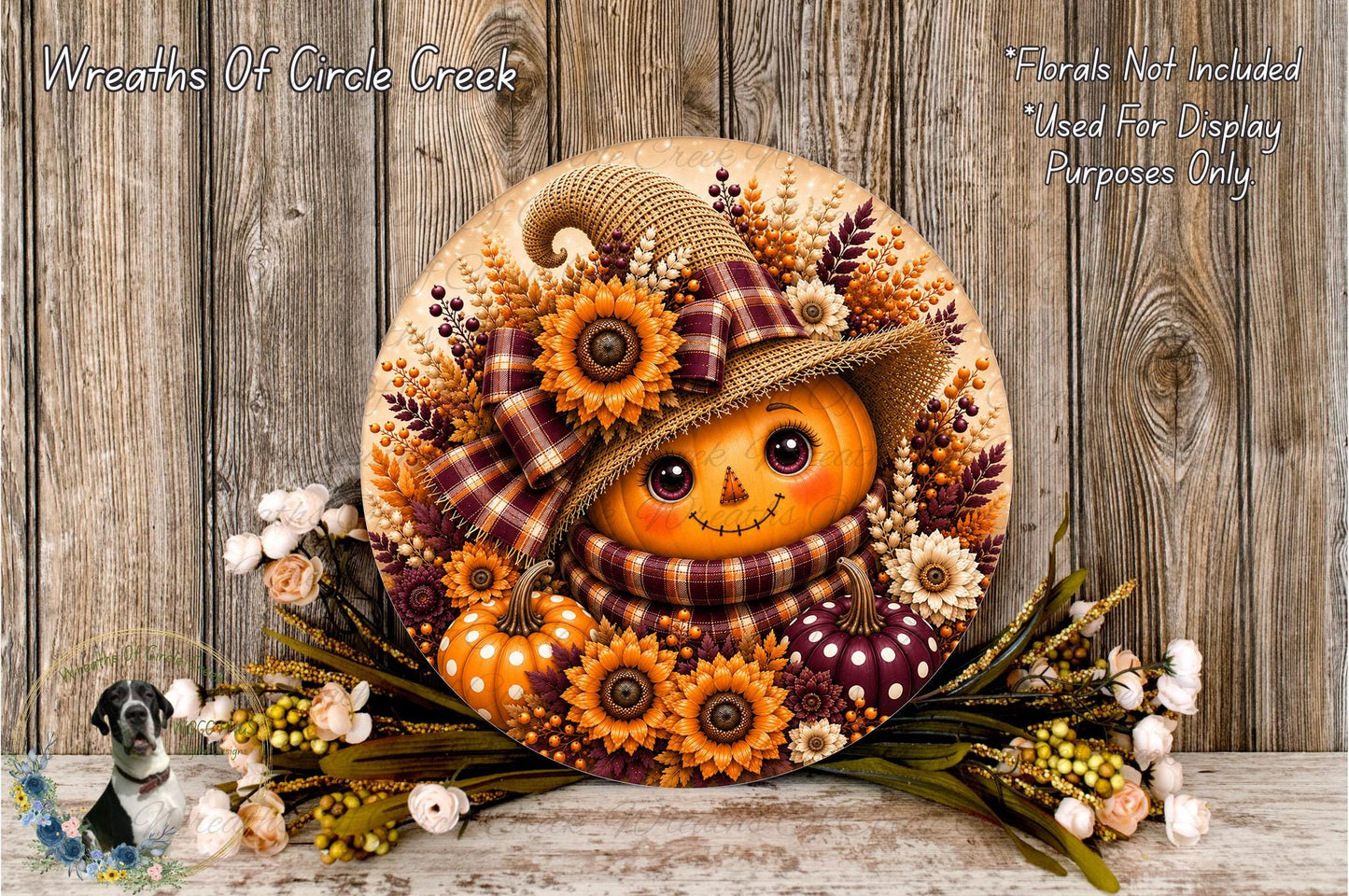A decorative wreath featuring a pumpkin face, flowers, and a plaid hat, placed on a wooden surface.