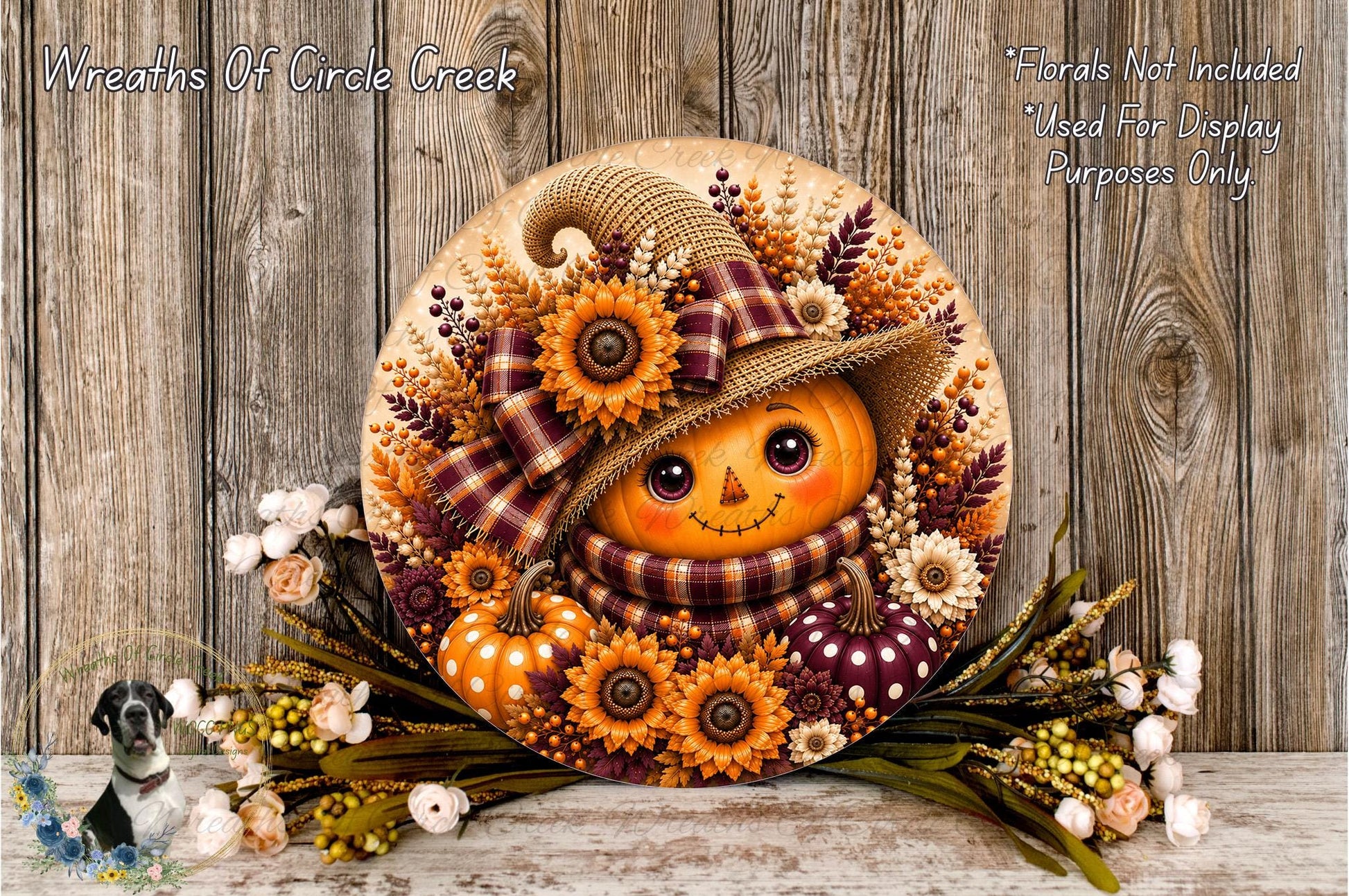 A decorative wreath featuring a pumpkin face, flowers, and a plaid hat, placed on a wooden surface.